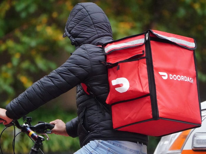 A DoorDash delivery person riding a bike